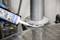 A person is applying white sealant from a cartridge to the seam of a metal surface in order to seal it.