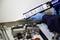 A person is applying sealant using a cartridge gun. Metal parts and tools are lying on the table.