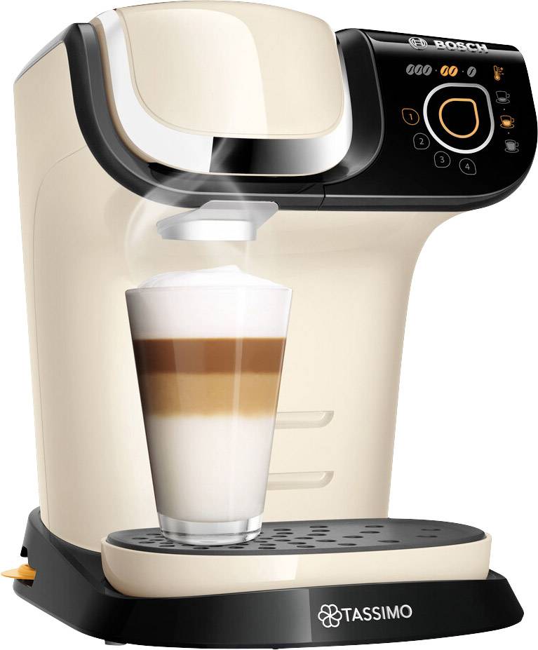 A Tassimo-branded coffee machine is preparing a latte macchiato in a transparent glass. Steam is rising from the glass.