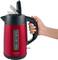 A hand is holding a red kettle with a black handle. The kettle has a transparent window with a water level indicator.