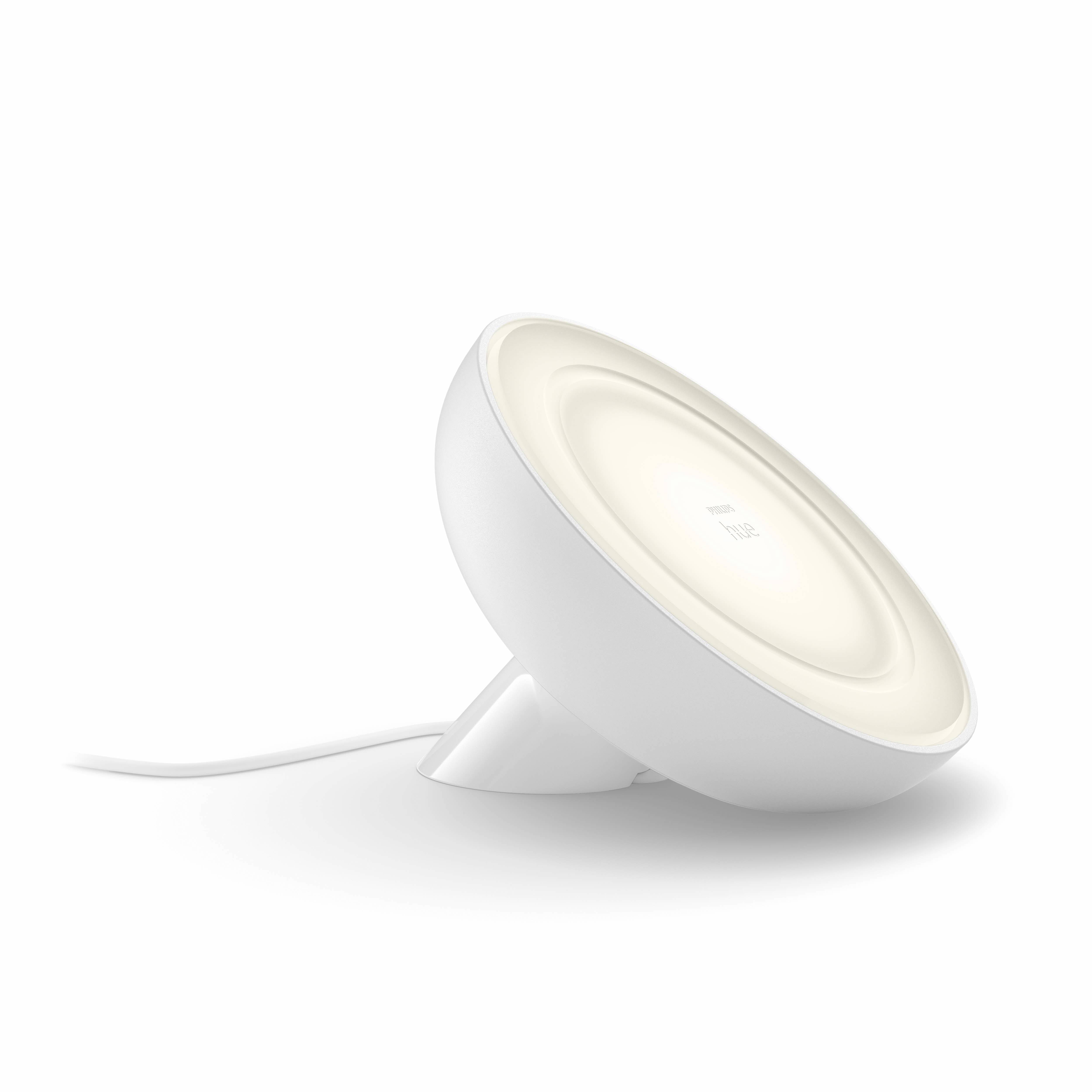 White table lamp with a round lampshade and cable, slightly tilted. It emits soft light and serves as accent lighting.