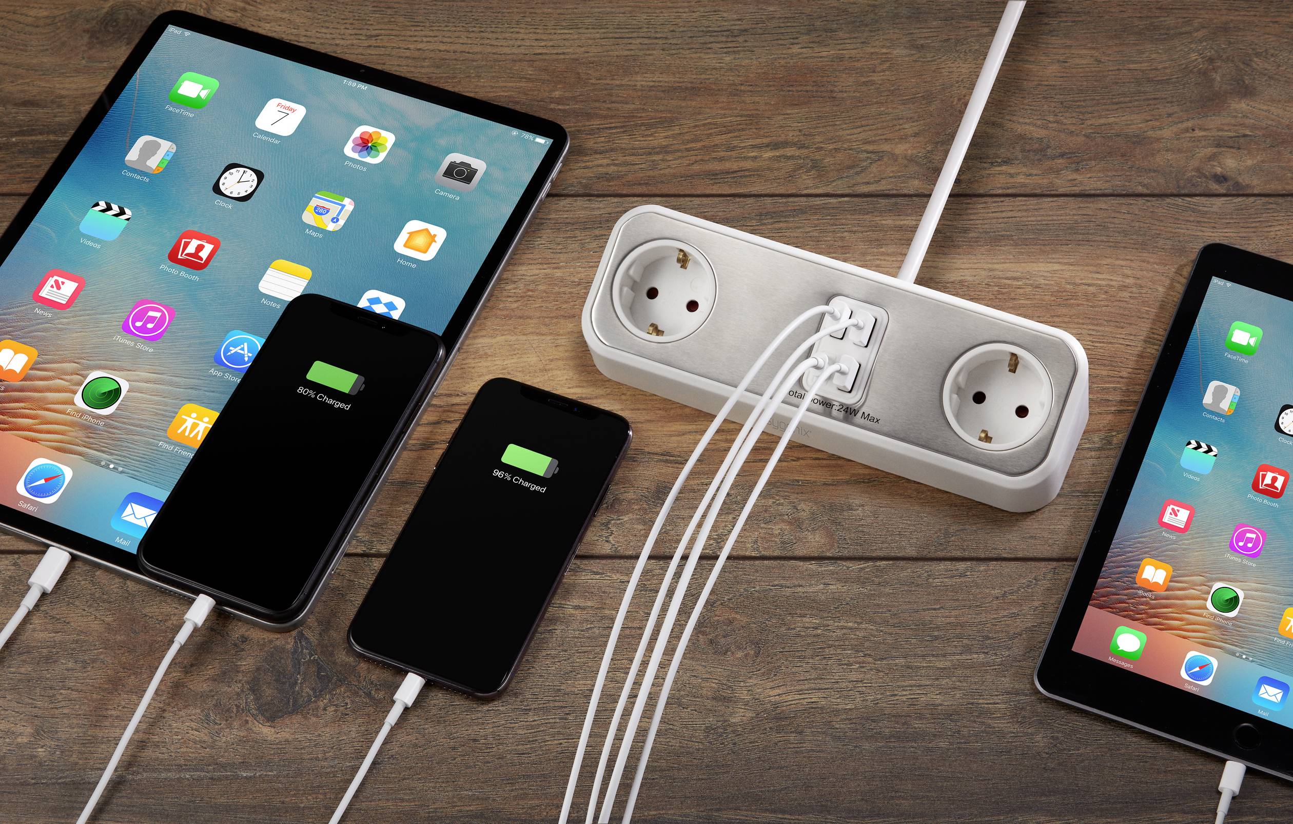 Tablet and smartphones are being charged simultaneously via an extension lead. All devices display their charging status.