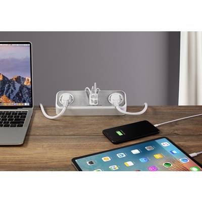A laptop, a power strip and two mobile devices are connected at a table, while a smartphone is being charged.