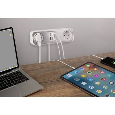 A laptop, tablet and smartphone are connected to a multi-socket outlet on the wall, placed on a table. The laptop has a grey display.