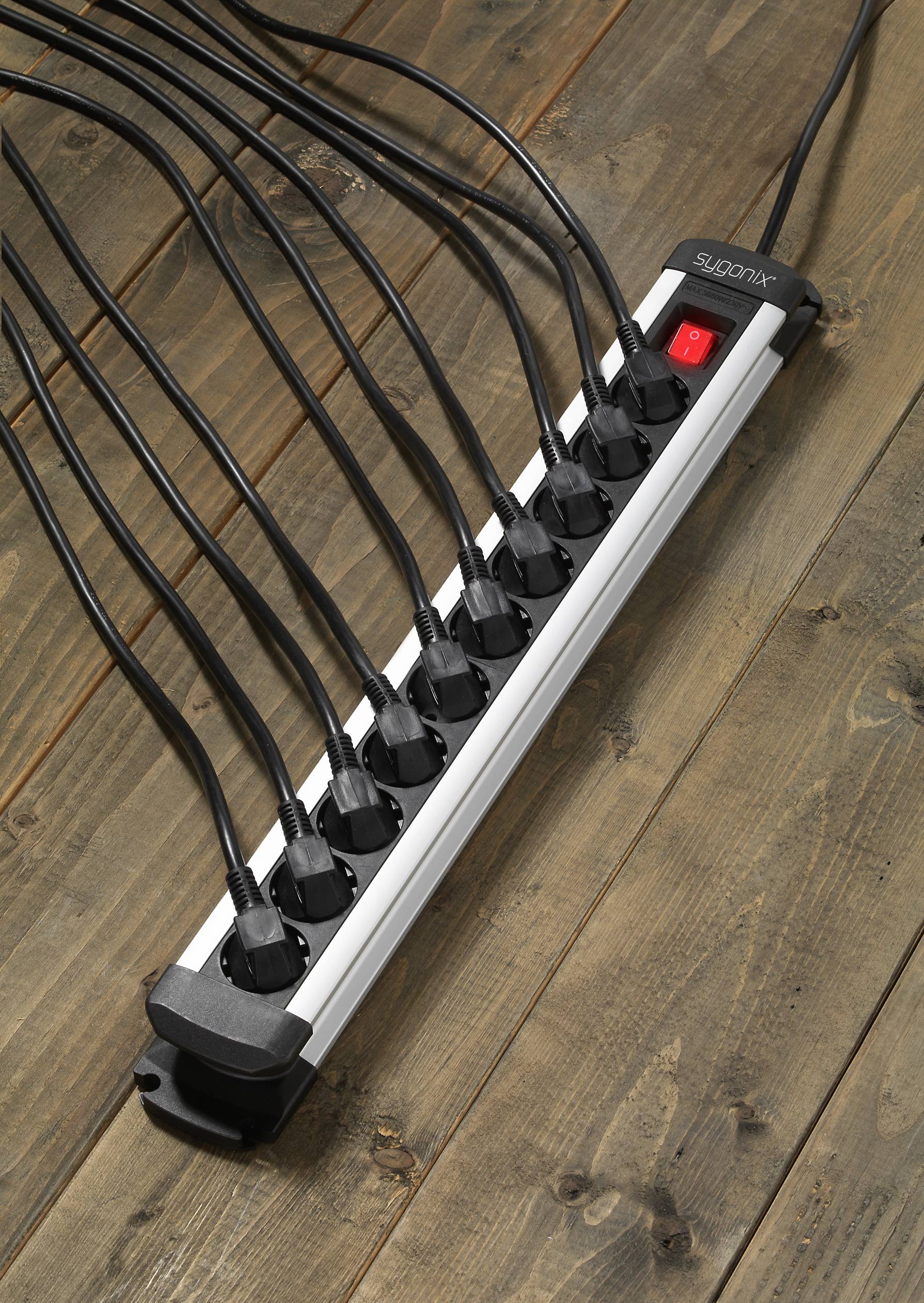 A multi-socket extension lead on a wooden floor, with all socket outlets occupied except one, and featuring a red power switch.