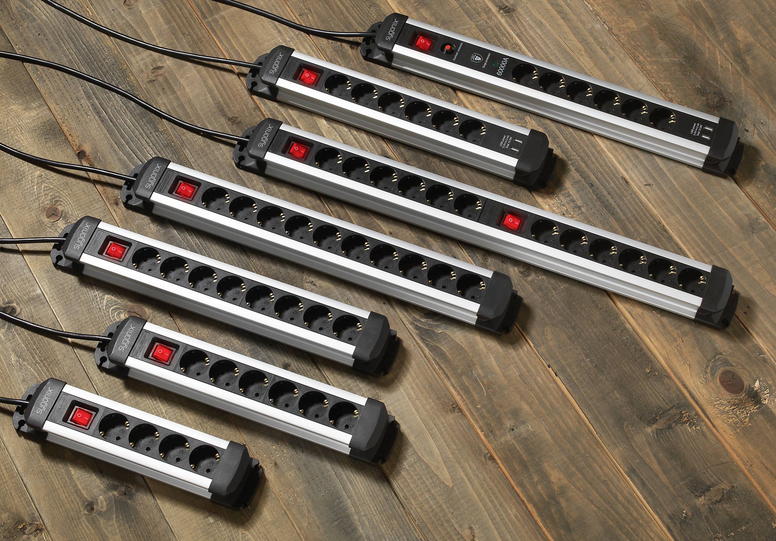 Several power strips in different sizes on a wooden floor. Each strip has red switches and multiple plug sockets.