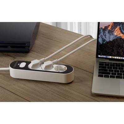 A laptop is connected to a power socket via an extension lead, which is situated on a wooden table. Next to the laptop is a black device.