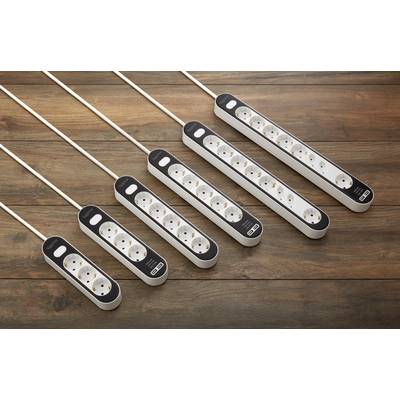Six white extension leads with varying numbers of power sockets are lying on a wooden floor.