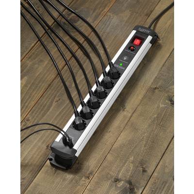 A black six-socket extension lead, all sockets in use. It is lying on a wooden floor. A red switch is turned on.