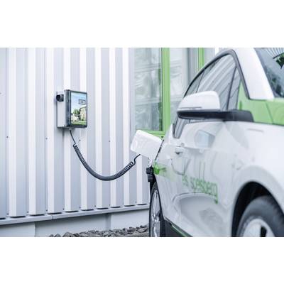 An electric car is being charged at a charging point on the wall of a building. The car is white with green accents.