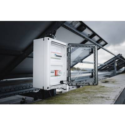 Electrical cabinet outdoors, open. It shows circuit breakers and wiring, installed on a solar installation beneath an overcast sky.