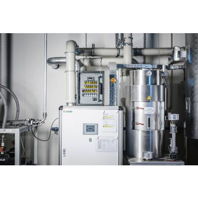 Industrial facility with pipelines, a control unit, and a metal container. Warning sign indicates caution.