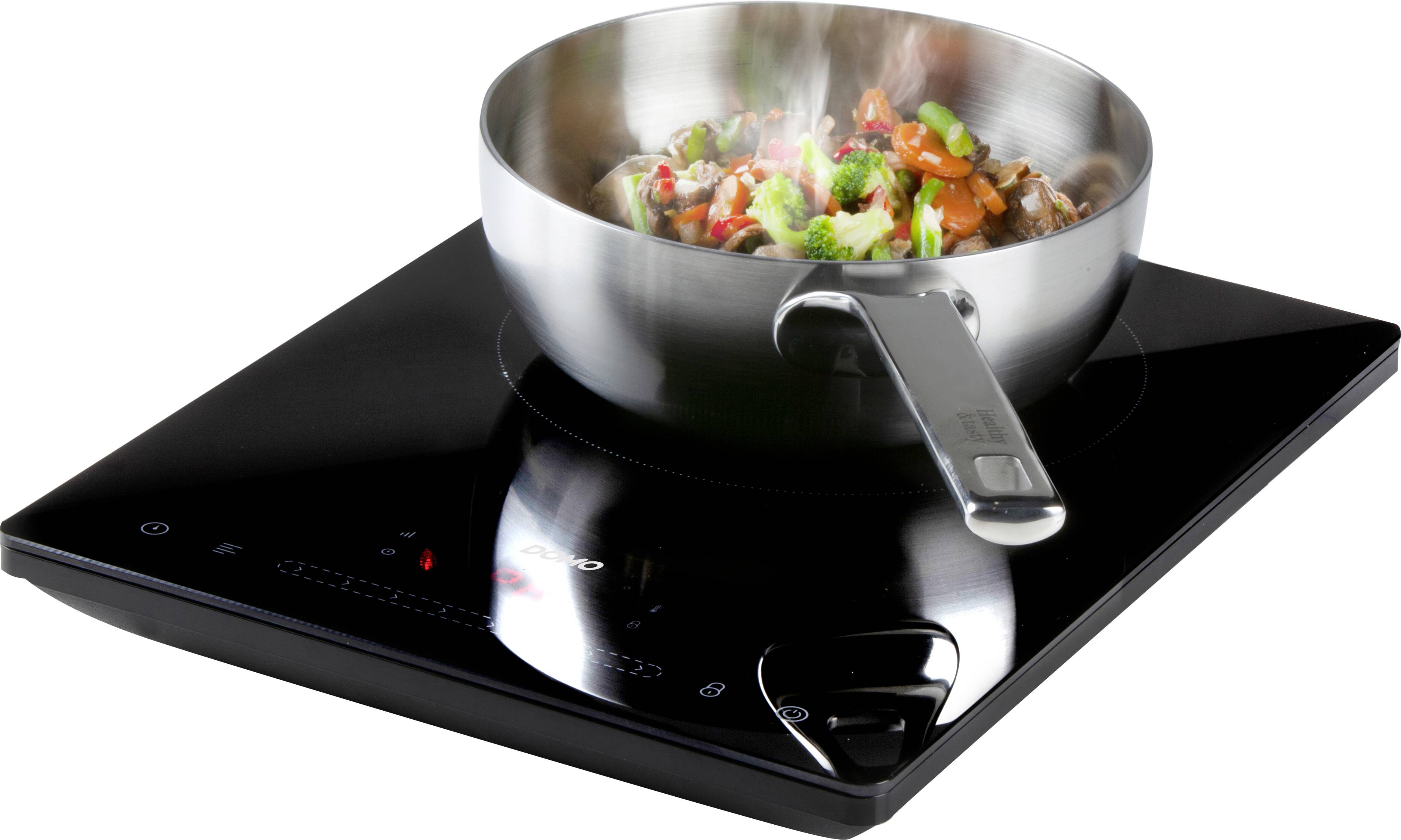 A pan with vegetables on a black induction hob, steam rising.