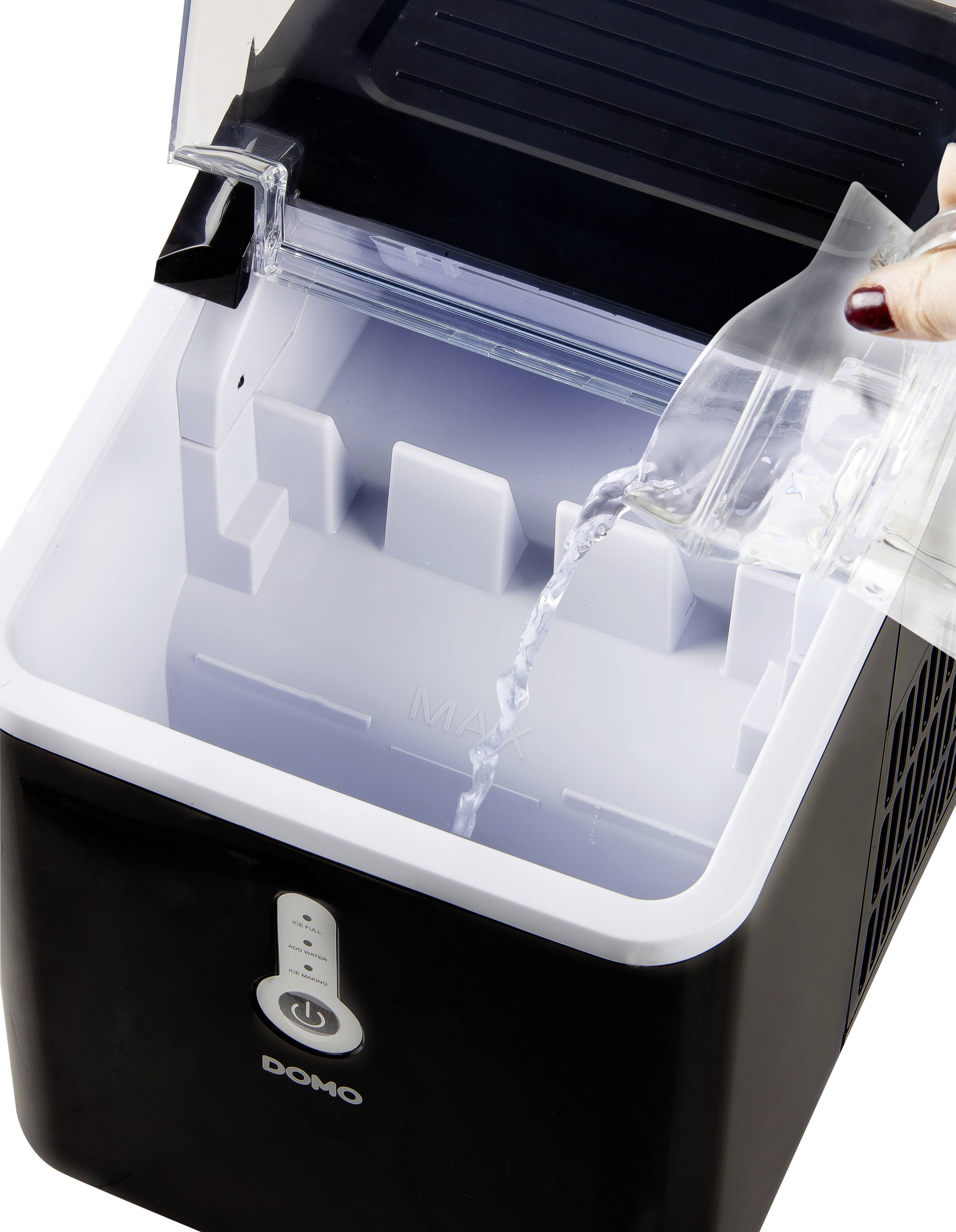 Rounded ice machine in a modern design. One hand fills water into it. Device prepares ice cubes.