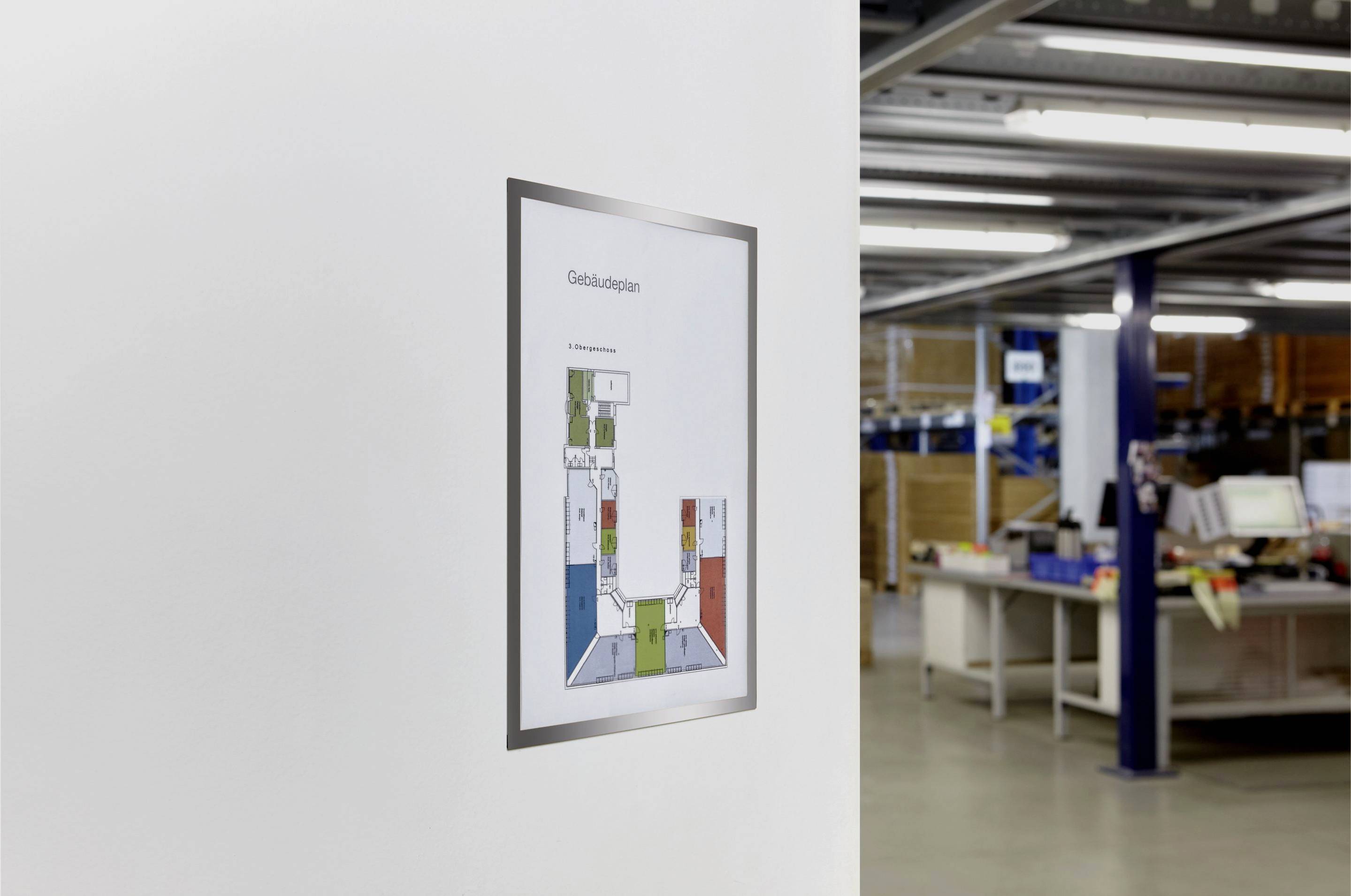 An evacuation plan is pinned to a white wall in an office with shelves and workstations in the background.