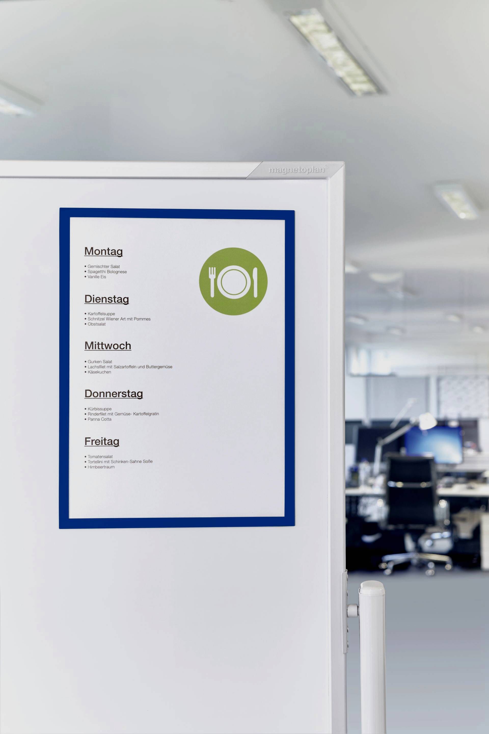 Menu board on an office wall, displaying the daily lunch special from Monday to Friday. Office in the background with empty desks.