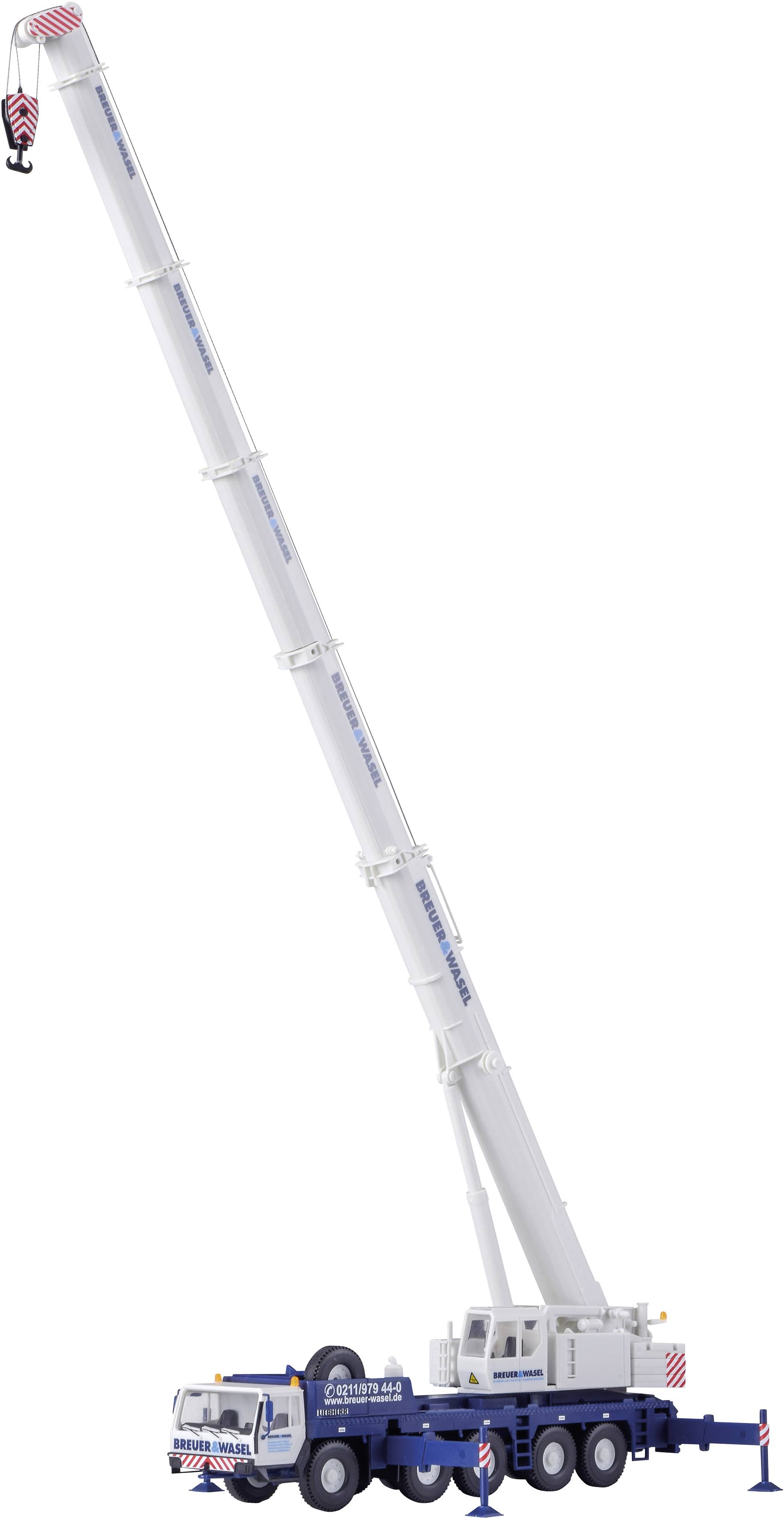 A white crane truck with an extended telescopic arm is parked on an asphalted surface. A person wearing blue clothing is standing nearby.