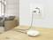 A white charger is plugged into a wall socket and is charging a wireless headphone case resting on a wooden table.