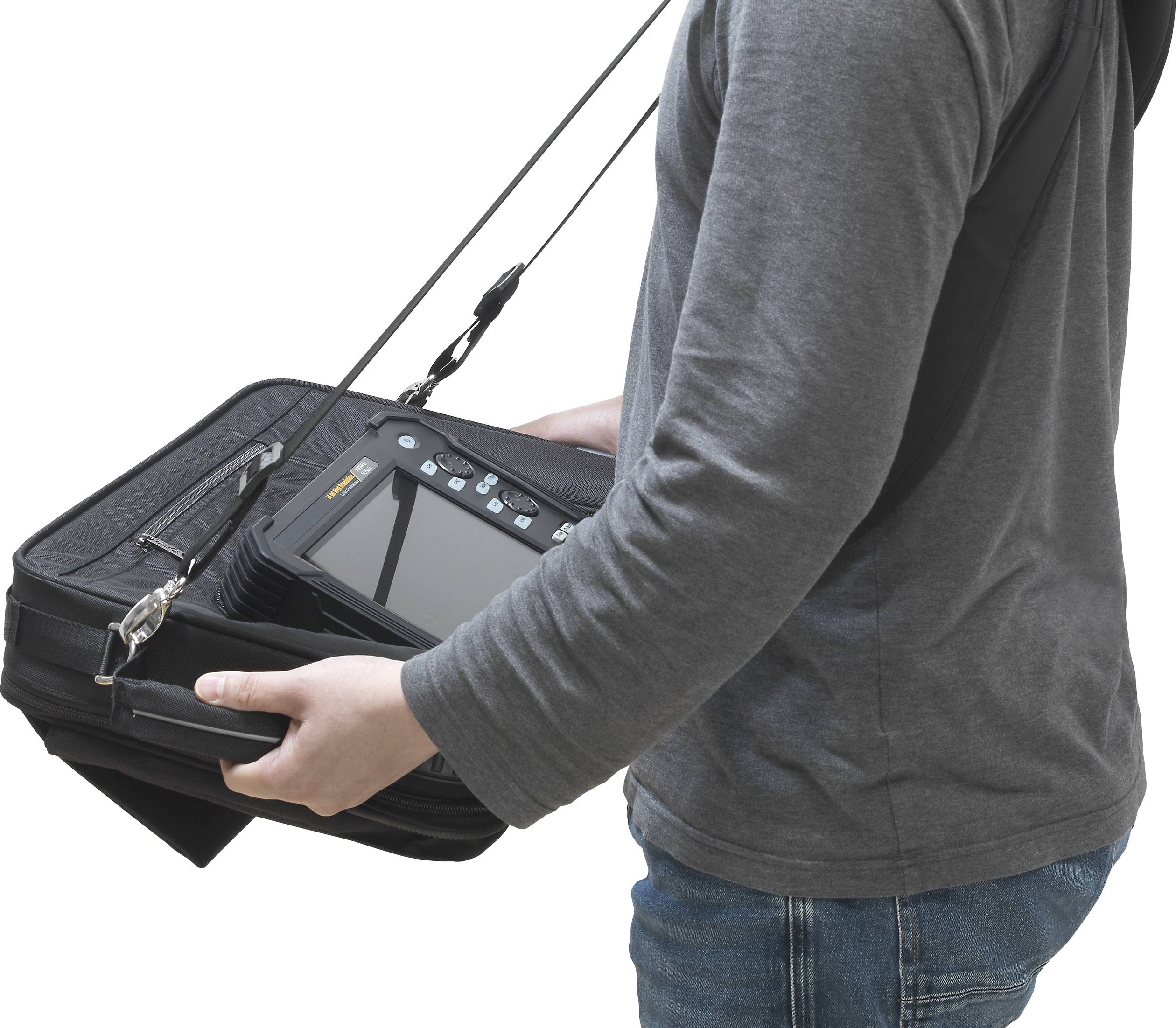 A person is wearing a portable device with a screen, attached to a shoulder strap. The device appears to be of a technical nature.