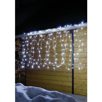 Fairy lights hang on a wooden building at night, casting a warm glow over the surrounding snow.