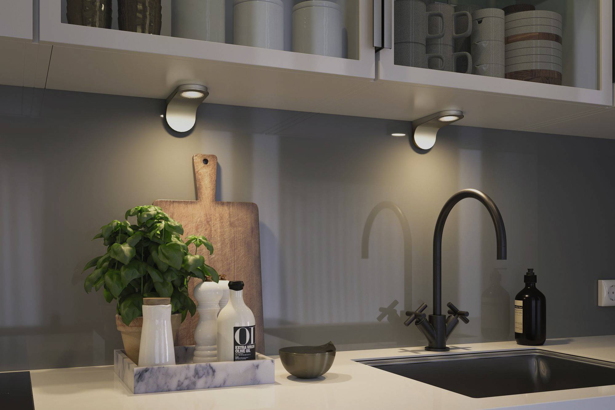 Kitchen worktop with sink, black tap, spice containers, plant and chopping board. Wall cupboards with crockery on top.