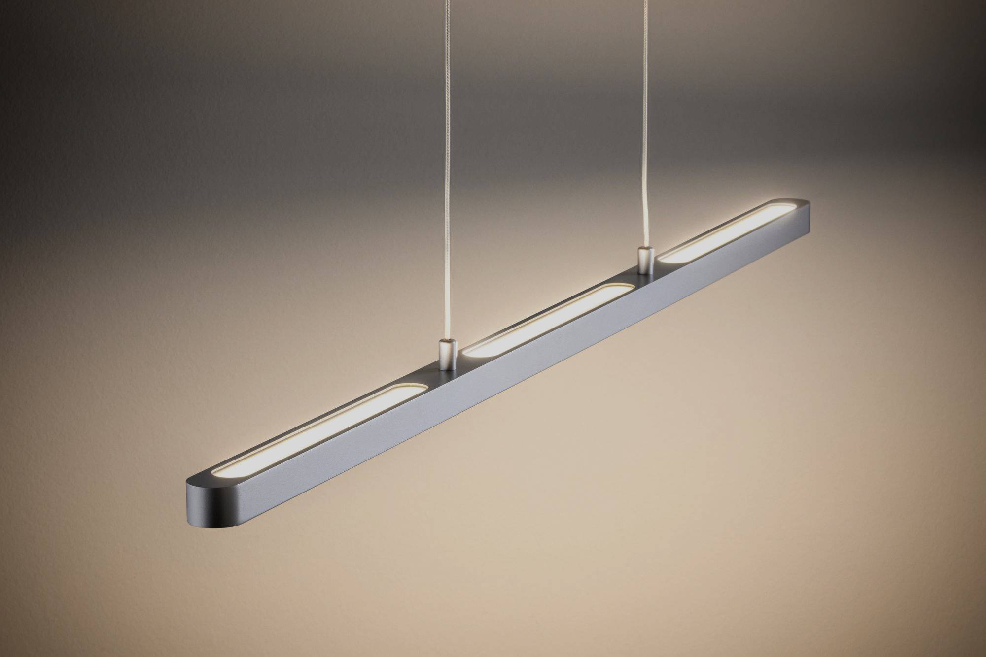 Suspended modern hanging light with minimalist design, two suspension cables, and even light distribution in a warm tone.
