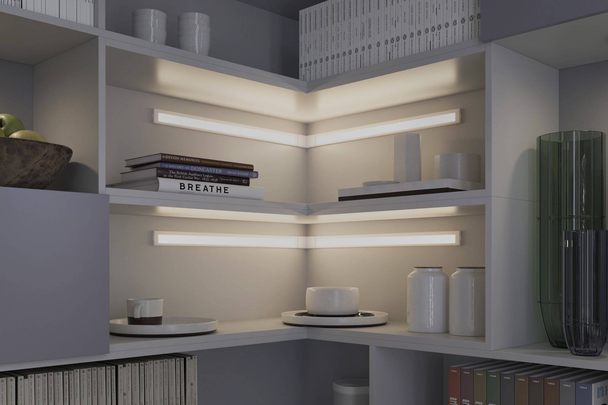 Corner shelving unit with illuminated shelves, displaying books, a fruit bowl, and decorative objects. Contemporary interior design.