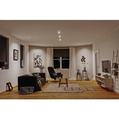 A modern furnished living room with a sofa, rug, armchair, coffee table and shelving. Subtle lighting and wall decoration.