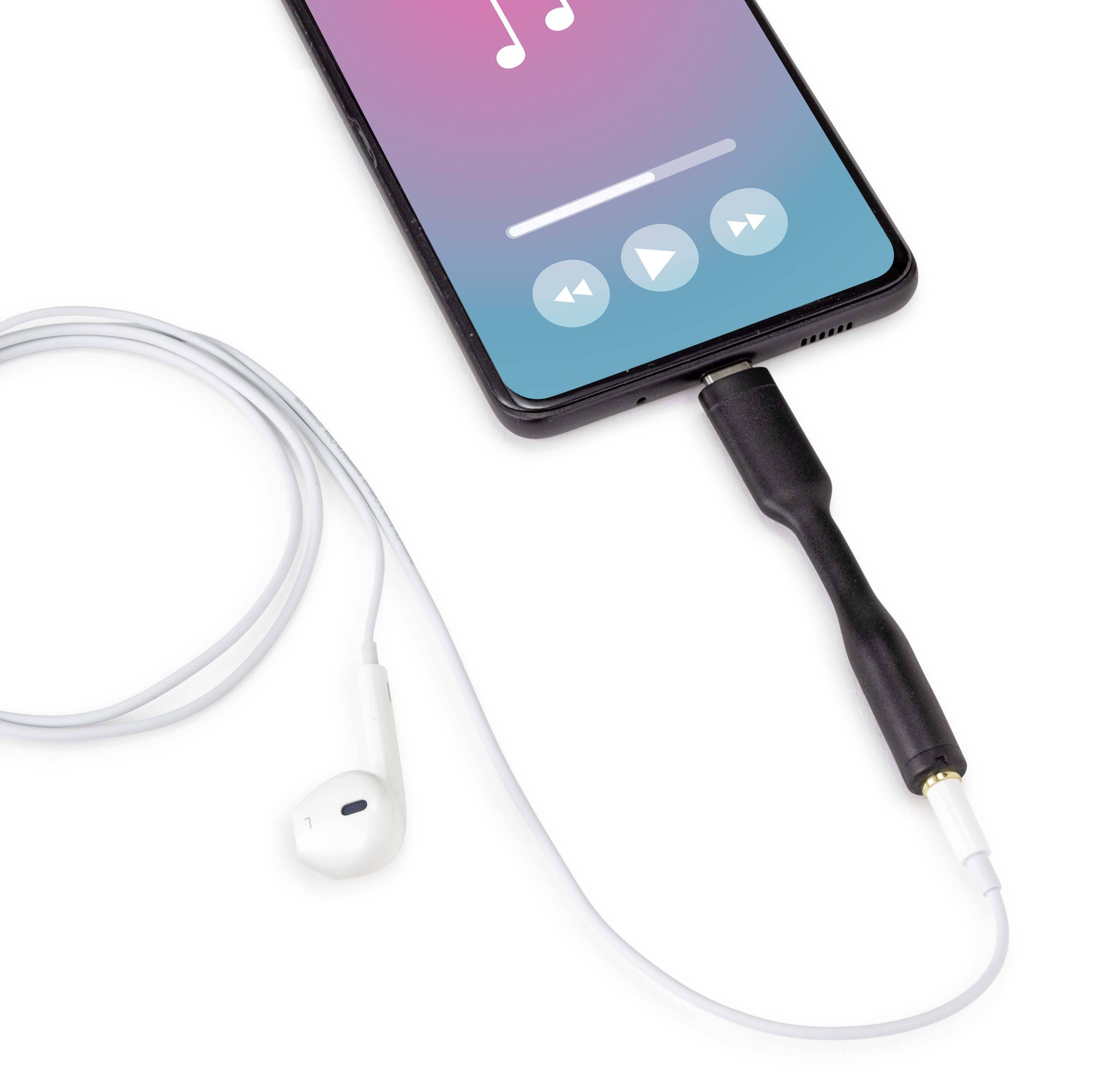 A smartphone with a music player display is connected via an adapter to wired white headphones, ready for music playback.