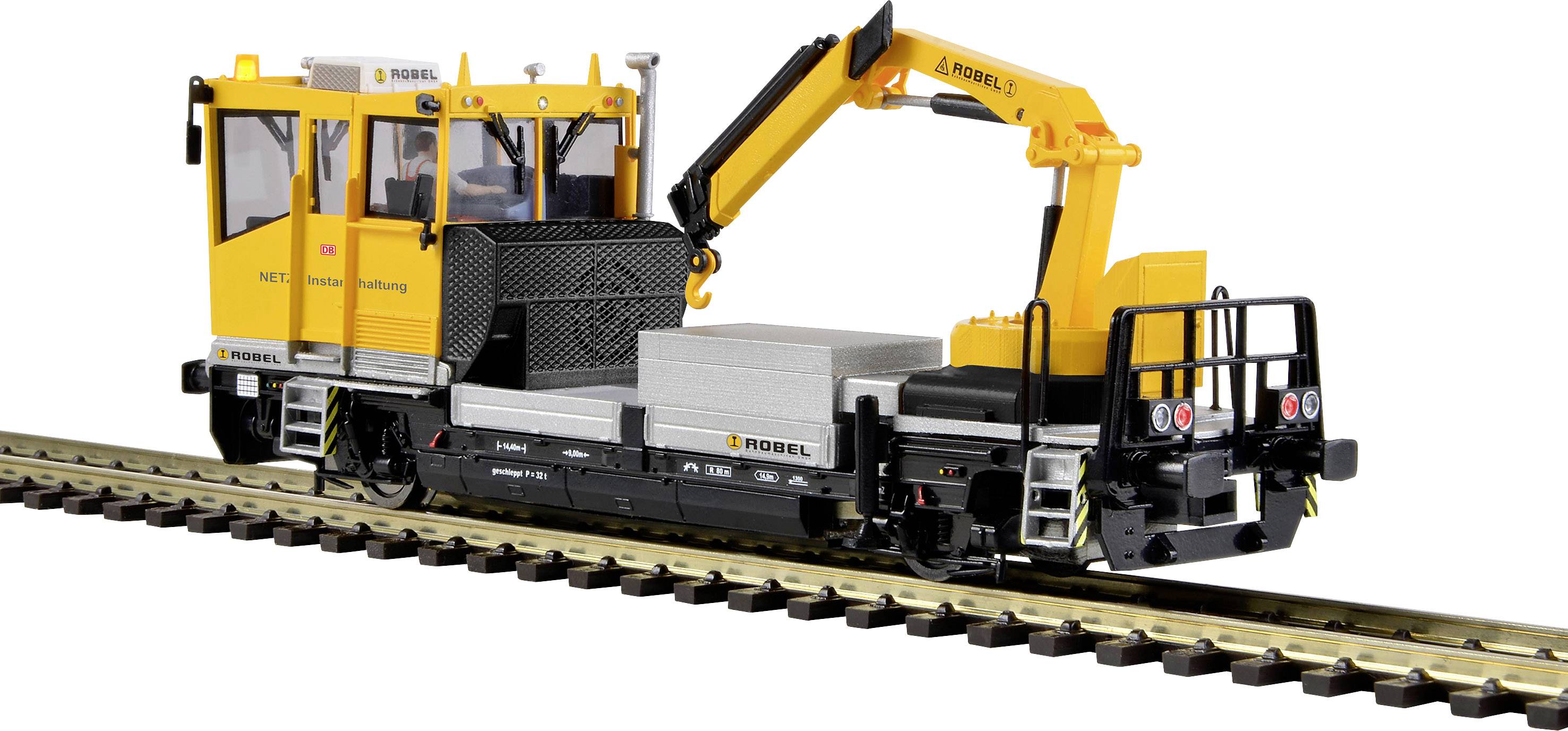A yellow rail vehicle with a crane is standing on railway tracks. It is equipped with construction equipment and designed for maintenance work.
