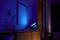 A smart projector casts blue light onto a white wall, illuminating a modern living room with furniture and decorations.