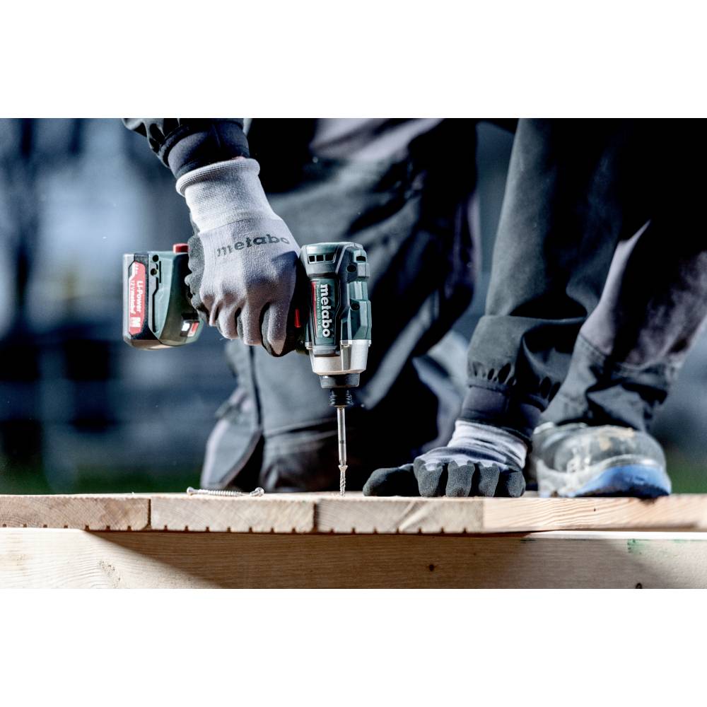 A person using a cordless power drill to fasten screws into wooden planks, wearing gloves for safety.