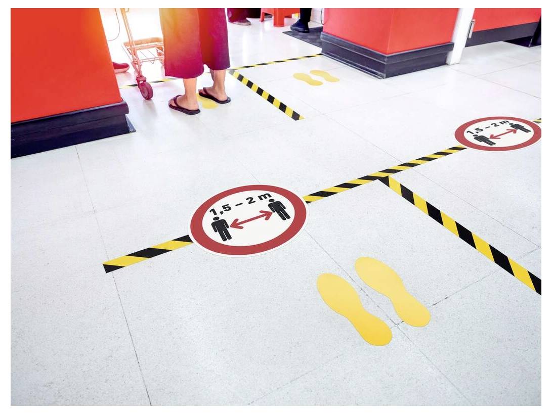 Floor markings in a store indicate social distancing with yellow footsteps and signs showing '1.5-2m' between customers at checkout.