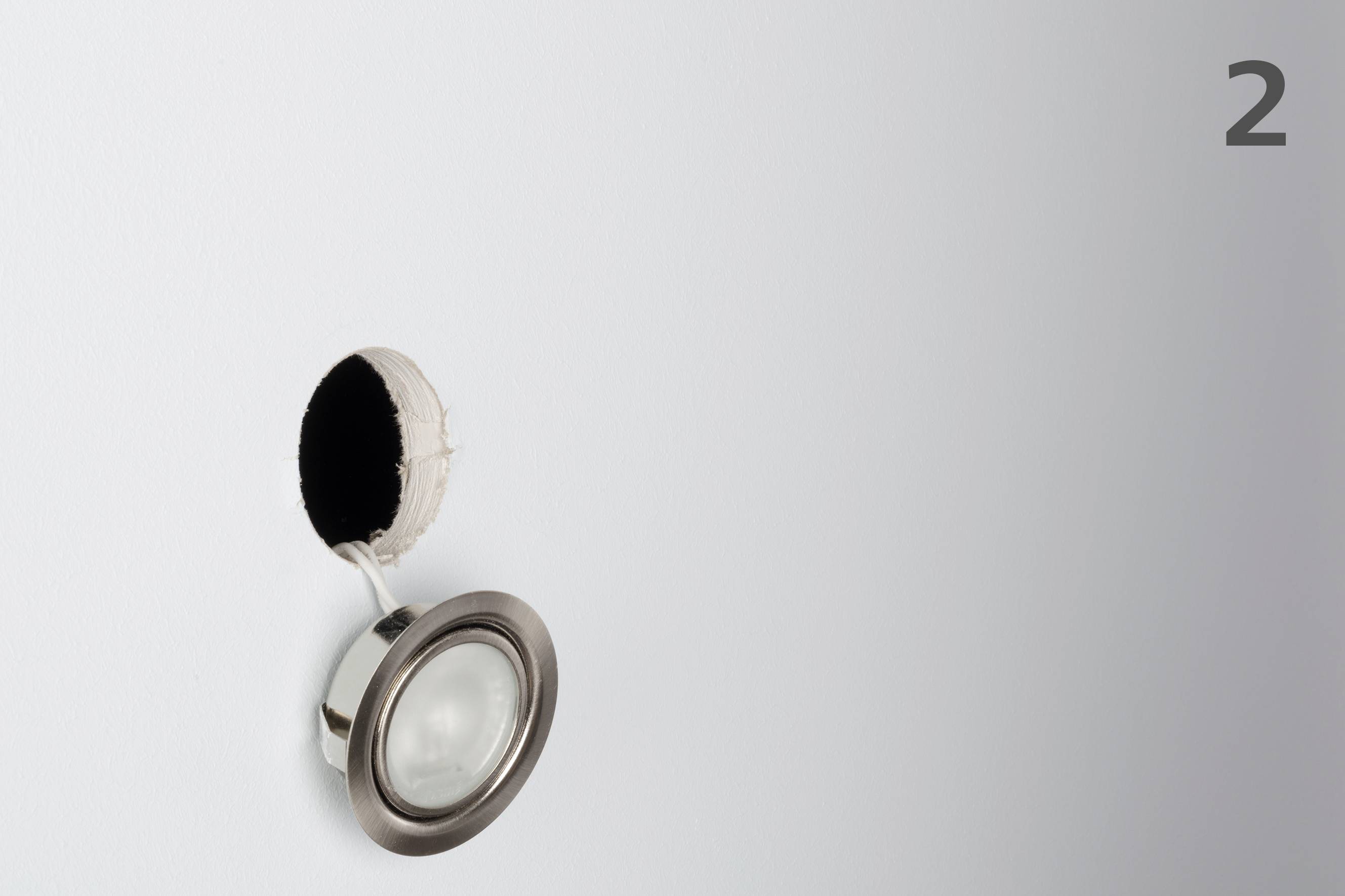 A ceiling light lies beneath a hole in the wall from which it has been removed. The number '2' is written in the top right.
