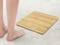 A person is standing barefoot next to an elegant bamboo weighing scale on a concrete floor.