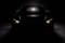 A black car in the darkness, with only the headlights illuminating, creating a dramatic and mysterious atmosphere.