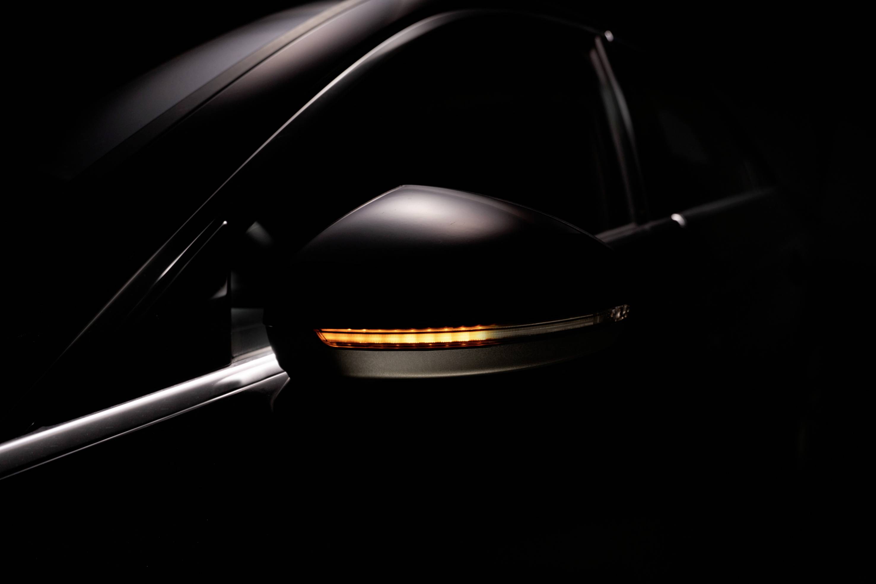 A car with its indicator on at the side, half-hidden in the shade.