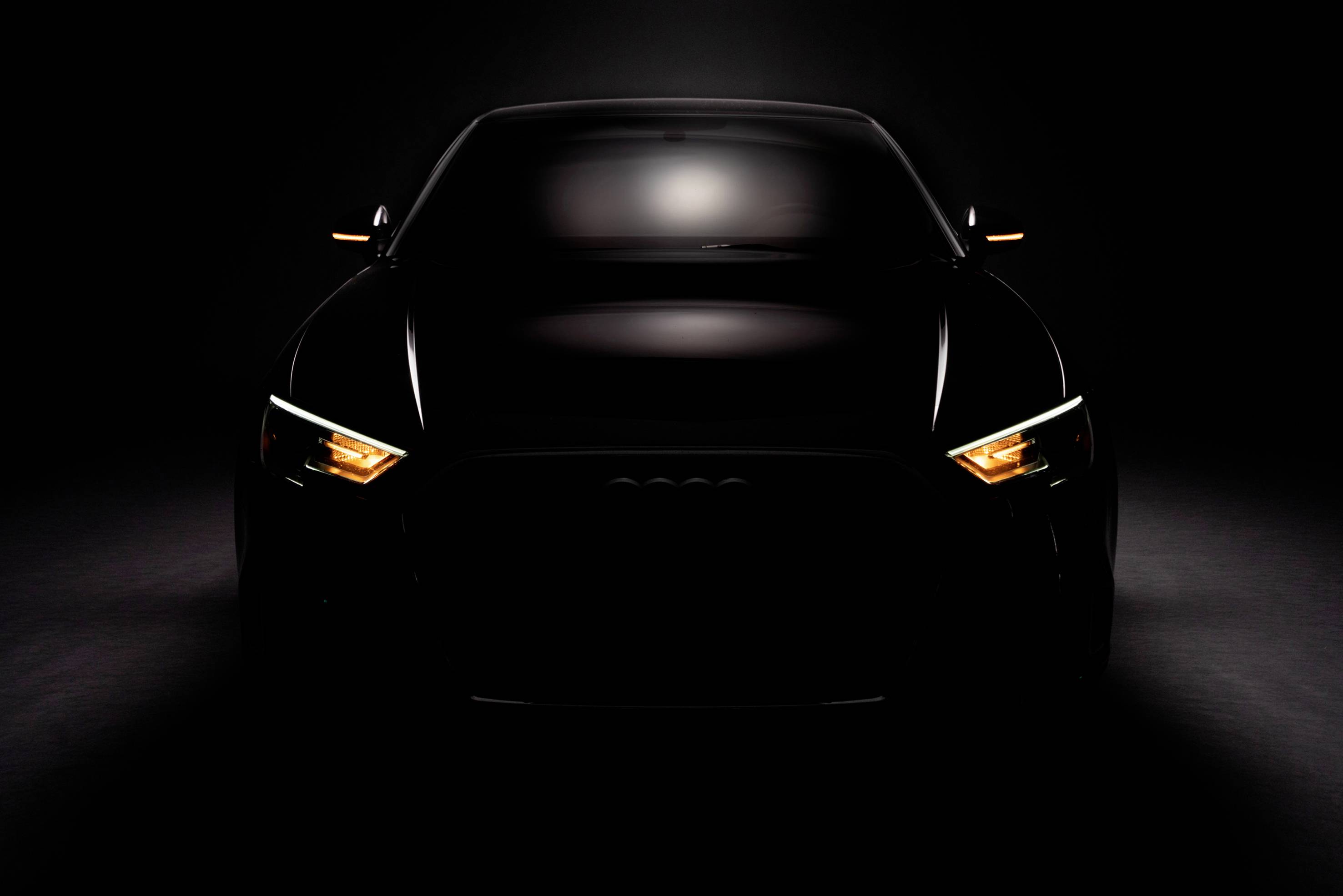 A car in a dark environment with activated headlights, showcasing a distinctive and modern design.