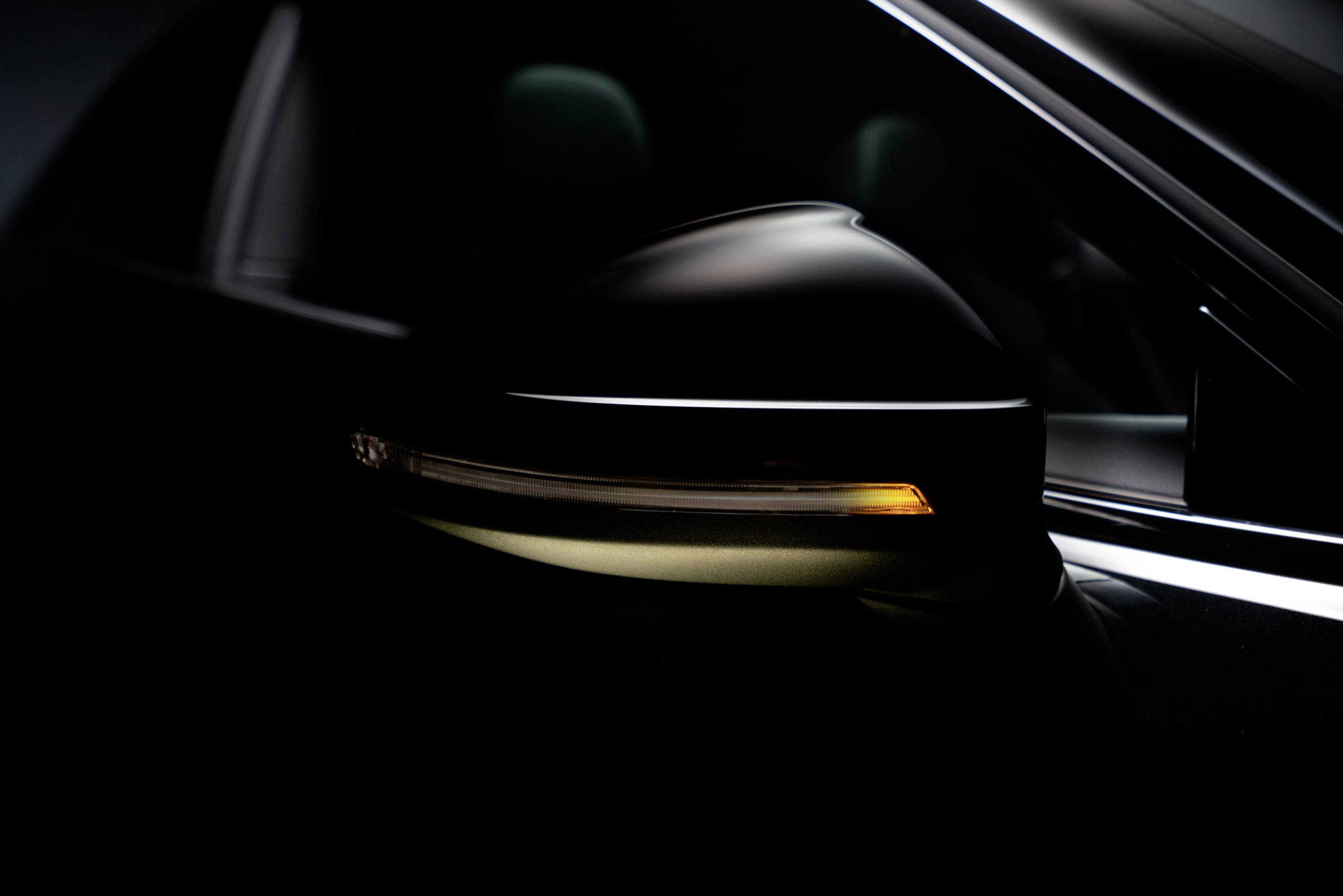 A car wing mirror with an illuminated indicator in a dark environment.