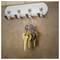 A ring of assorted keys hangs on a wall-mounted hook rack with five silver hooks against a brown tiled background.