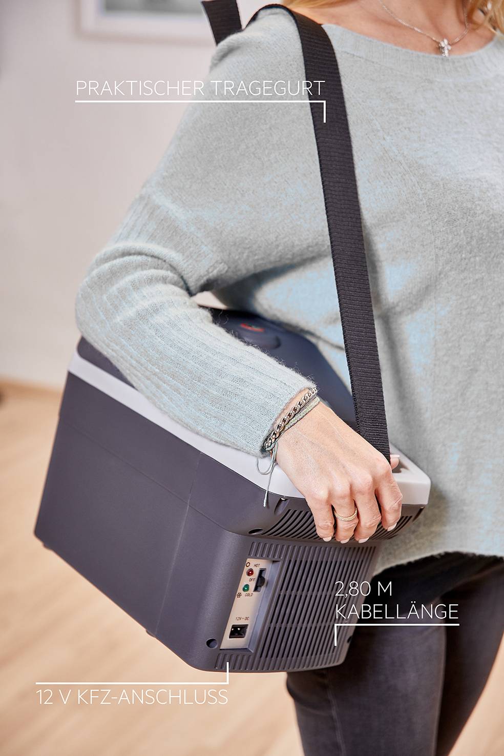 A person is carrying a portable cool box with a convenient carrying strap. On the box it reads 'Convenient Carrying Strap', '2.80 m Cable Length', '12 V Car Socket Connection'.