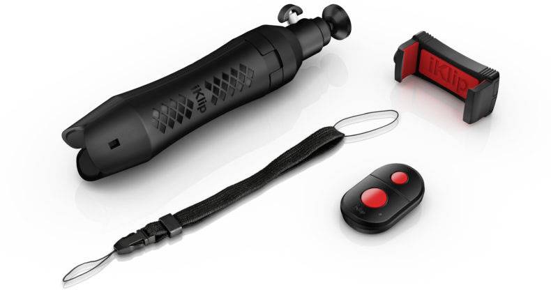 A black selfie stick with a mount and remote control, including a hand strap, is lying on a white background.