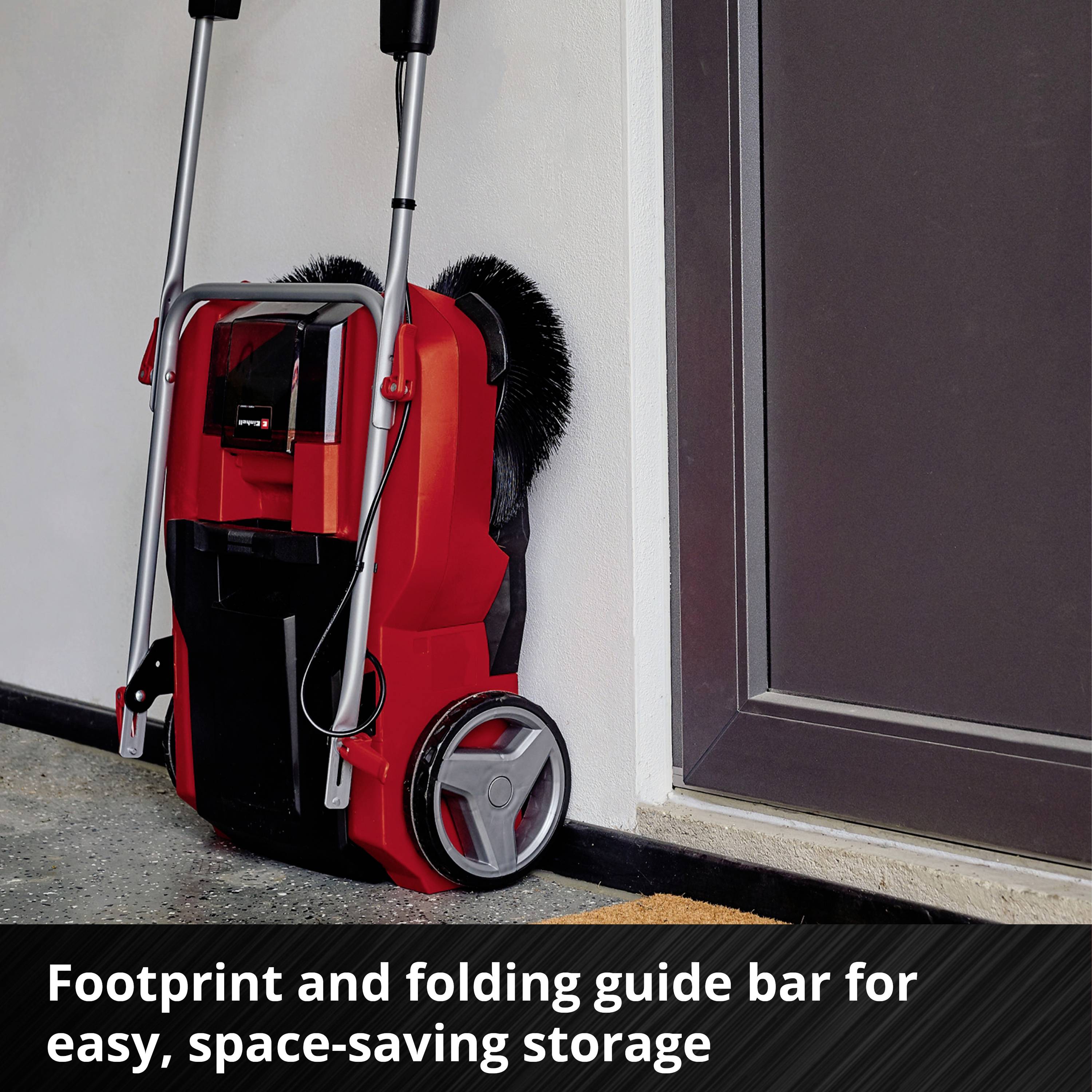 A red pressure washer with a folding handle stands next to a wall. The text describes its easy and space-saving storage.