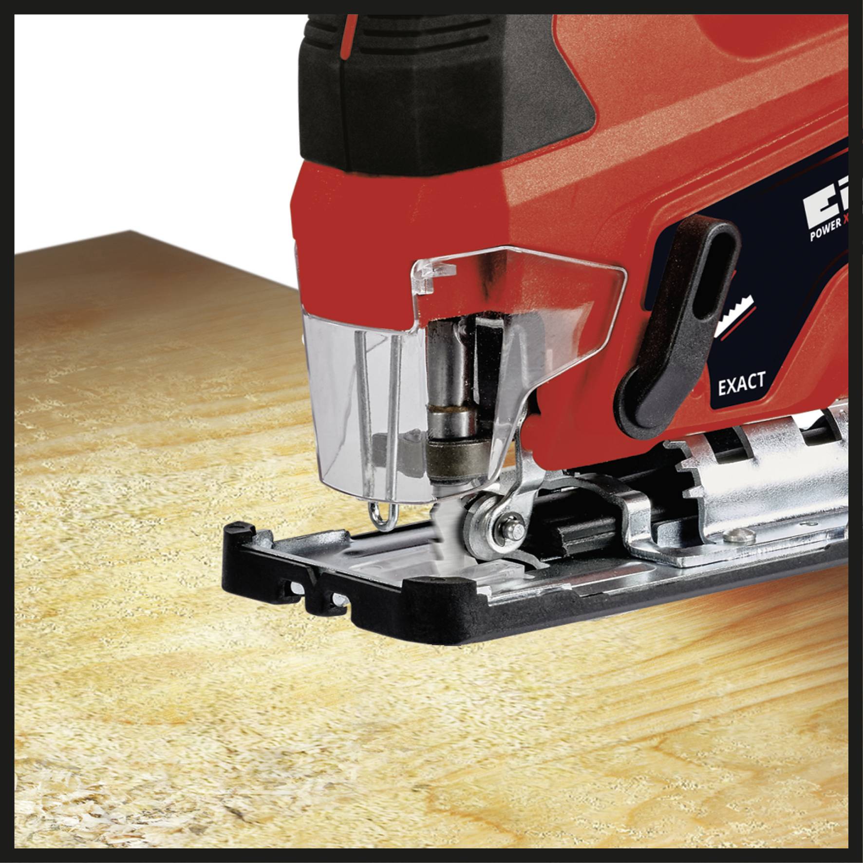 A red jigsaw saw cuts through a piece of wood on a workbench. The saw has an unusually shaped saw blade.