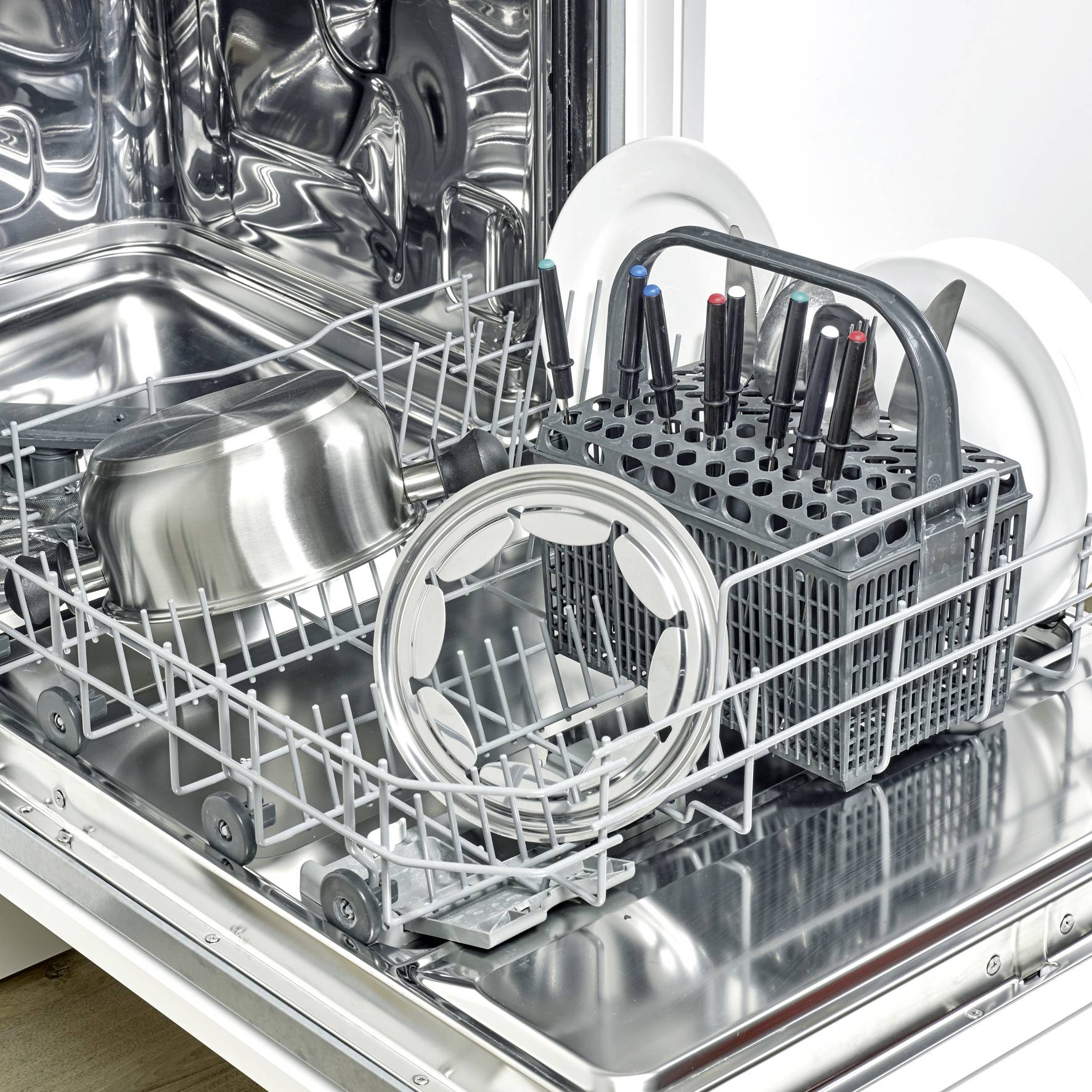 An open dishwasher loaded with pots, lids, plates, and a cutlery basket.