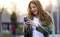 Woman with long hair smiles and looks at her smartphone outdoors.