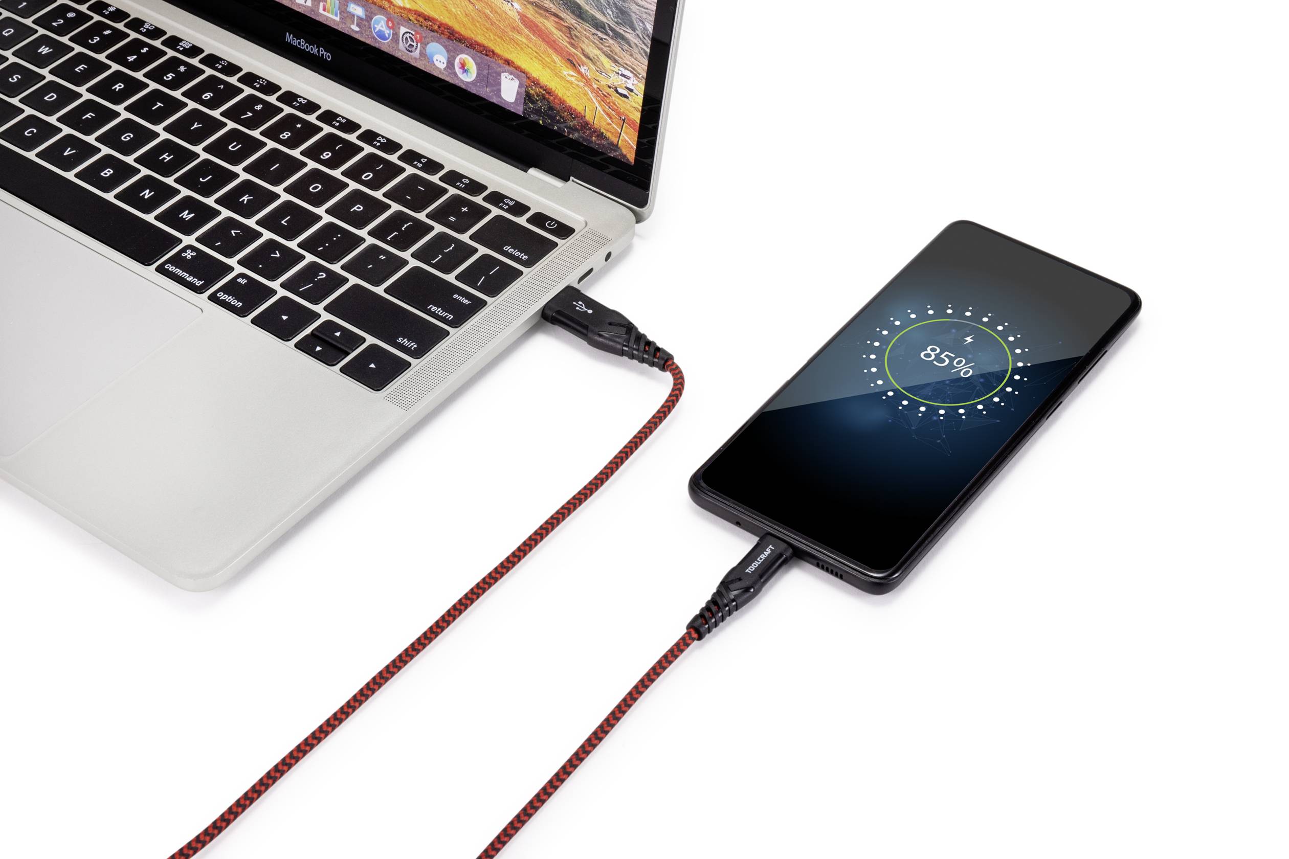 A smartphone is connected to a laptop via a red cable and displays a battery level of 85%.