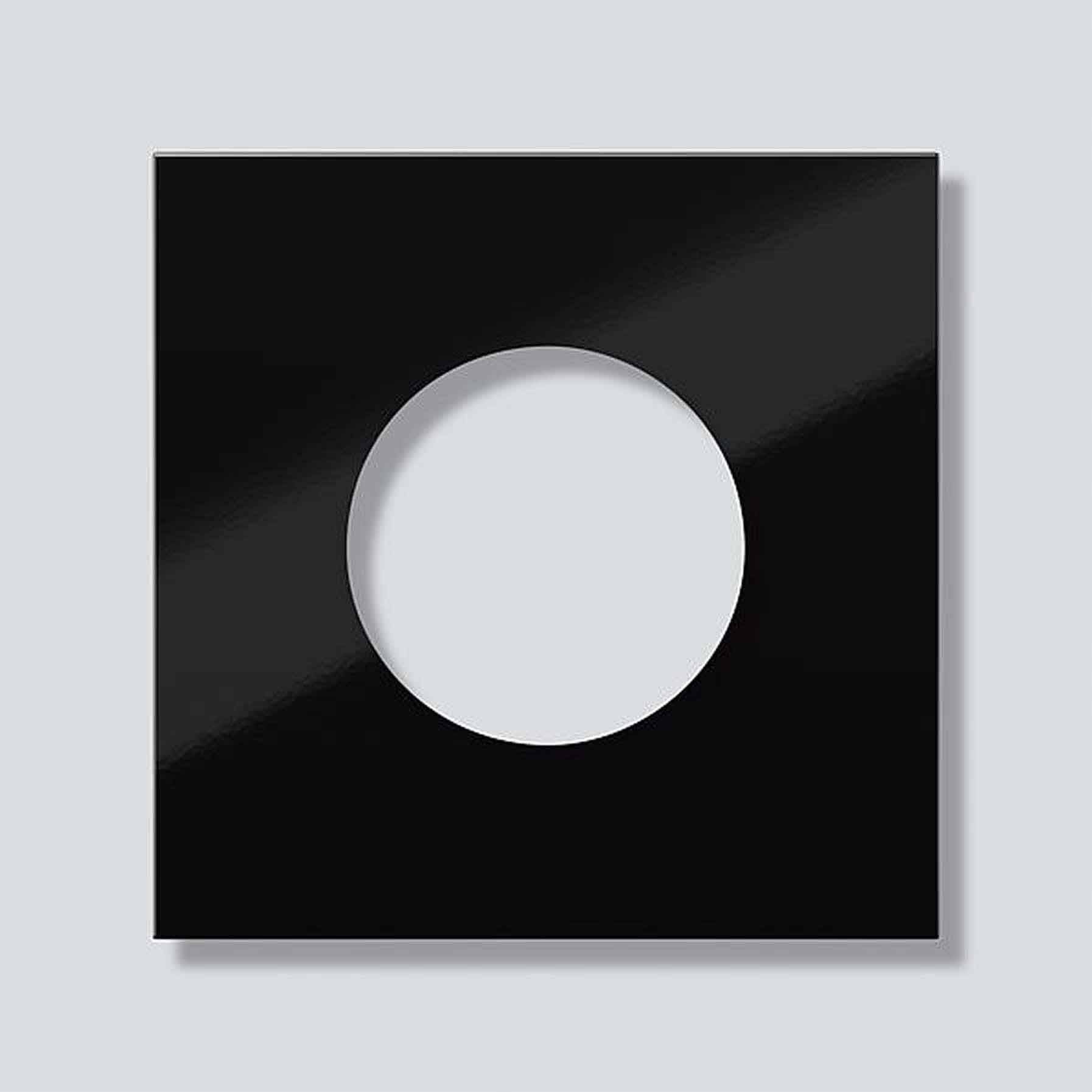 Black square with a circular cut-out in the centre against a grey background. Minimalist design object.
