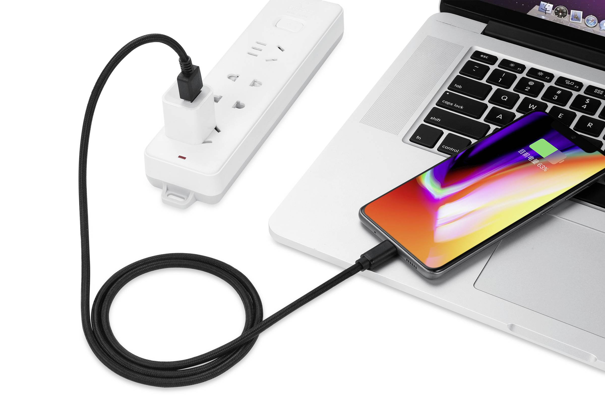 A smartphone is connected to a laptop via a USB cable. The laptop is situated next to a power strip with a plug inserted.