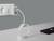A smartphone on a table is charging with a spiral cable connected to a charger plugged into a wall socket.